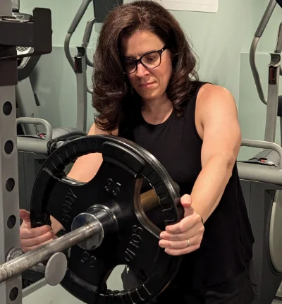 Athena putting plates onto a barbell in her home gym